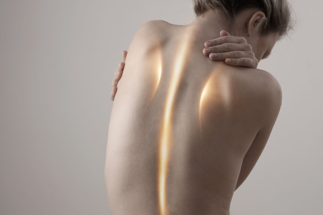 A woman's back and posture are shown, highlighting the shoulders and spine.